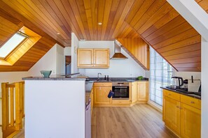 Eine moderne Küche mit Holzschnitzereien, einem eingebauten Ofen und einem großen Fenster, das für natürliches Licht sorgt.