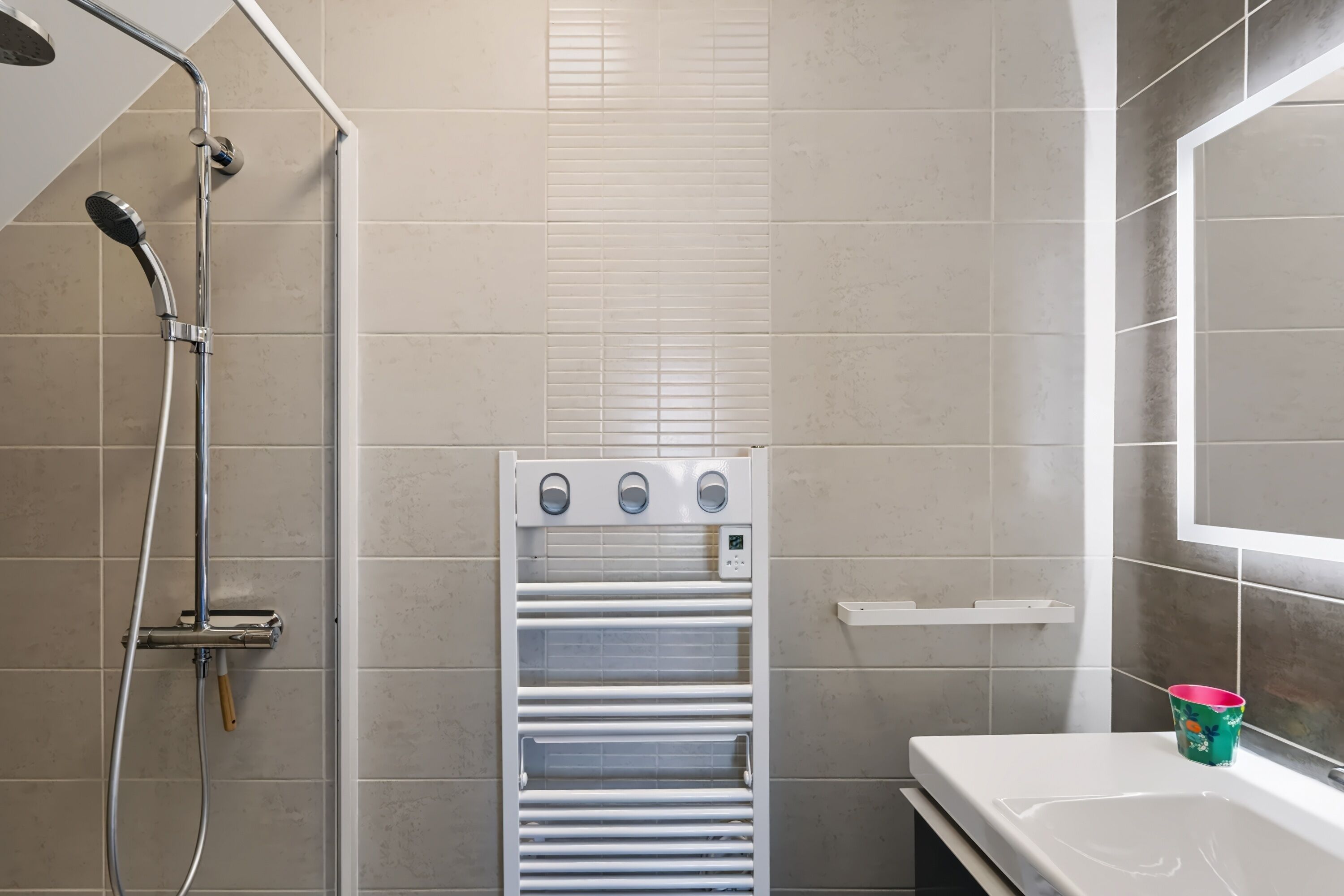 A bathroom with a shower, a towel rack, and a sink.
