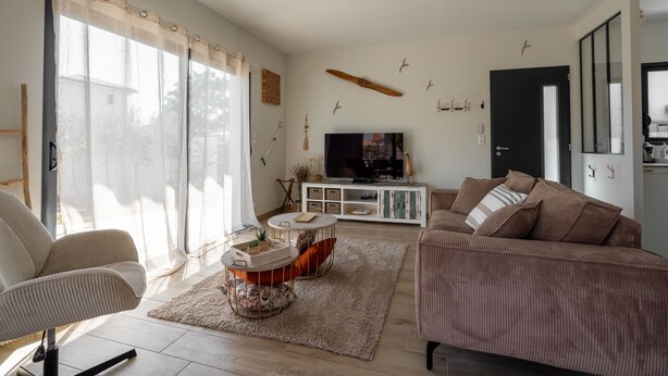 Una sala de estar con sofá, sillón, televisor y un adorno en la pared.