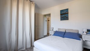 Un dormitorio con cama, mesita de noche, lámpara y un cuadro en la pared.