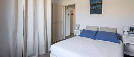 A bedroom with a bed, a nightstand, a lamp, and a painting on the wall.
