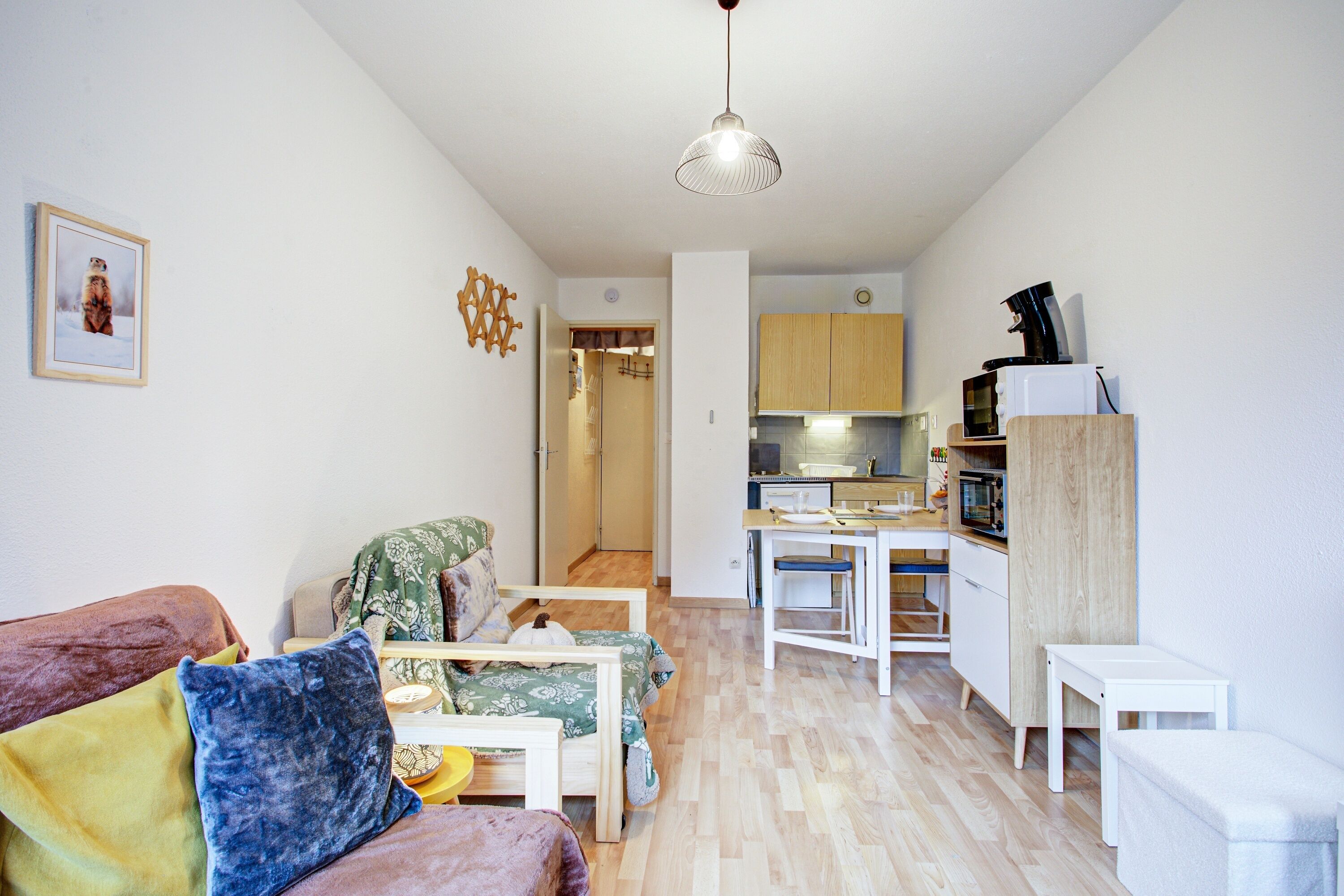 A compact living space with a sofa, a dining table, and a kitchenette.