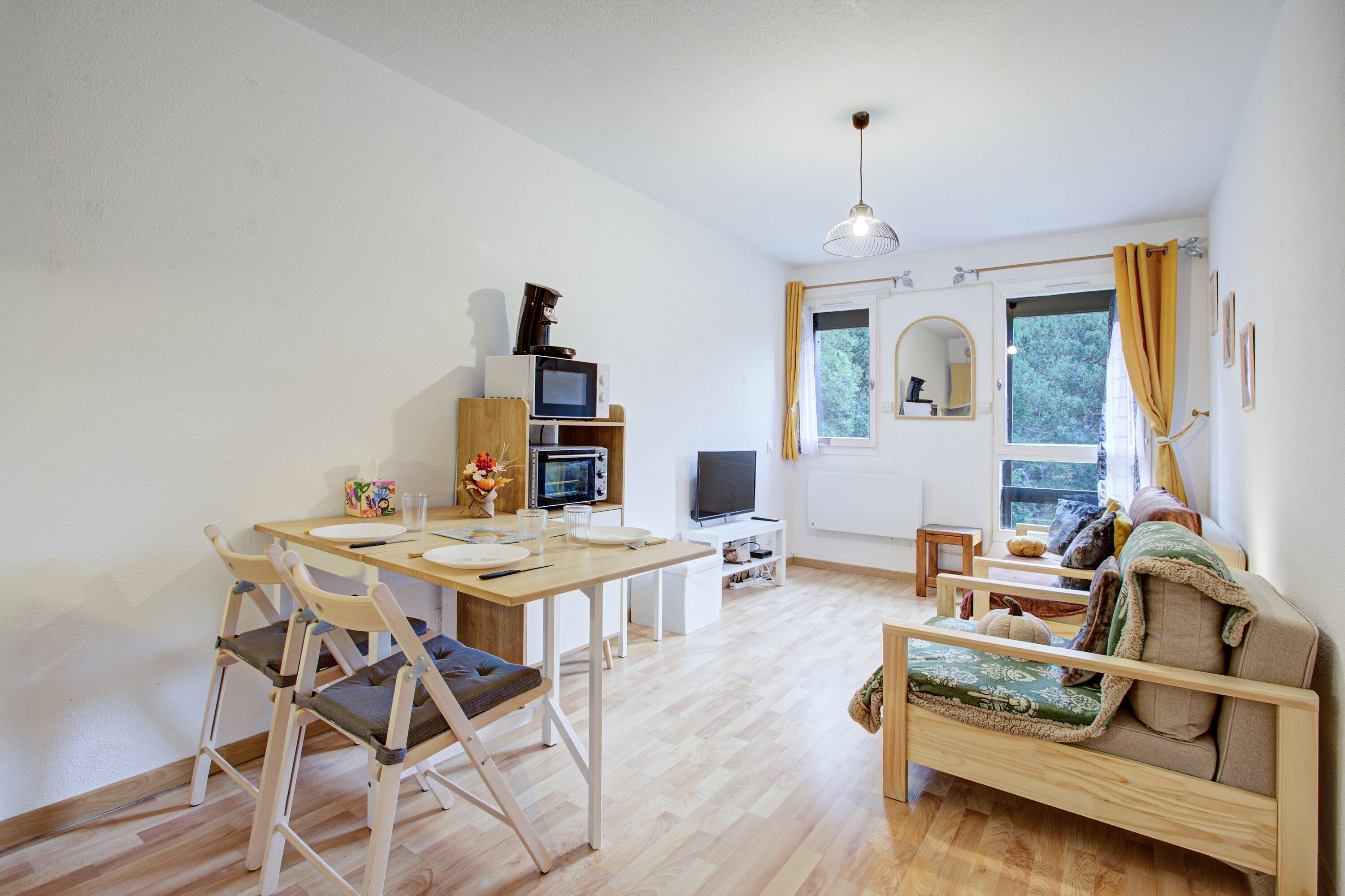 Ett modernt vardagsrum med ett matbord i trä, en soffa och en tv.