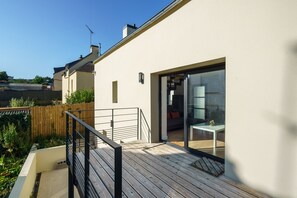 A modern house with a wooden deck, a glass door leading to a dining area, and a clear sky. - Ty Ker Briec - À 15 min de Quimper (Briec)