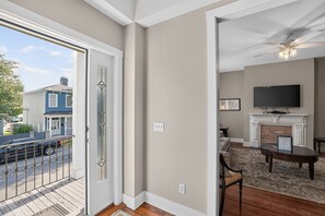 A living room with a fireplace, a television, and a dining area. - Change of Place Unit B - Victorian District (Savannah)