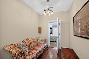 A hallway with a striped sofa, a wooden cabinet, and a framed picture on the wall. - Change of Place Unit B - Victorian District (Savannah)