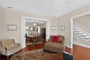 A living room with a sofa, armchair, and a dining area with chairs and a table. - Change of Place Unit B - Victorian District (Savannah)