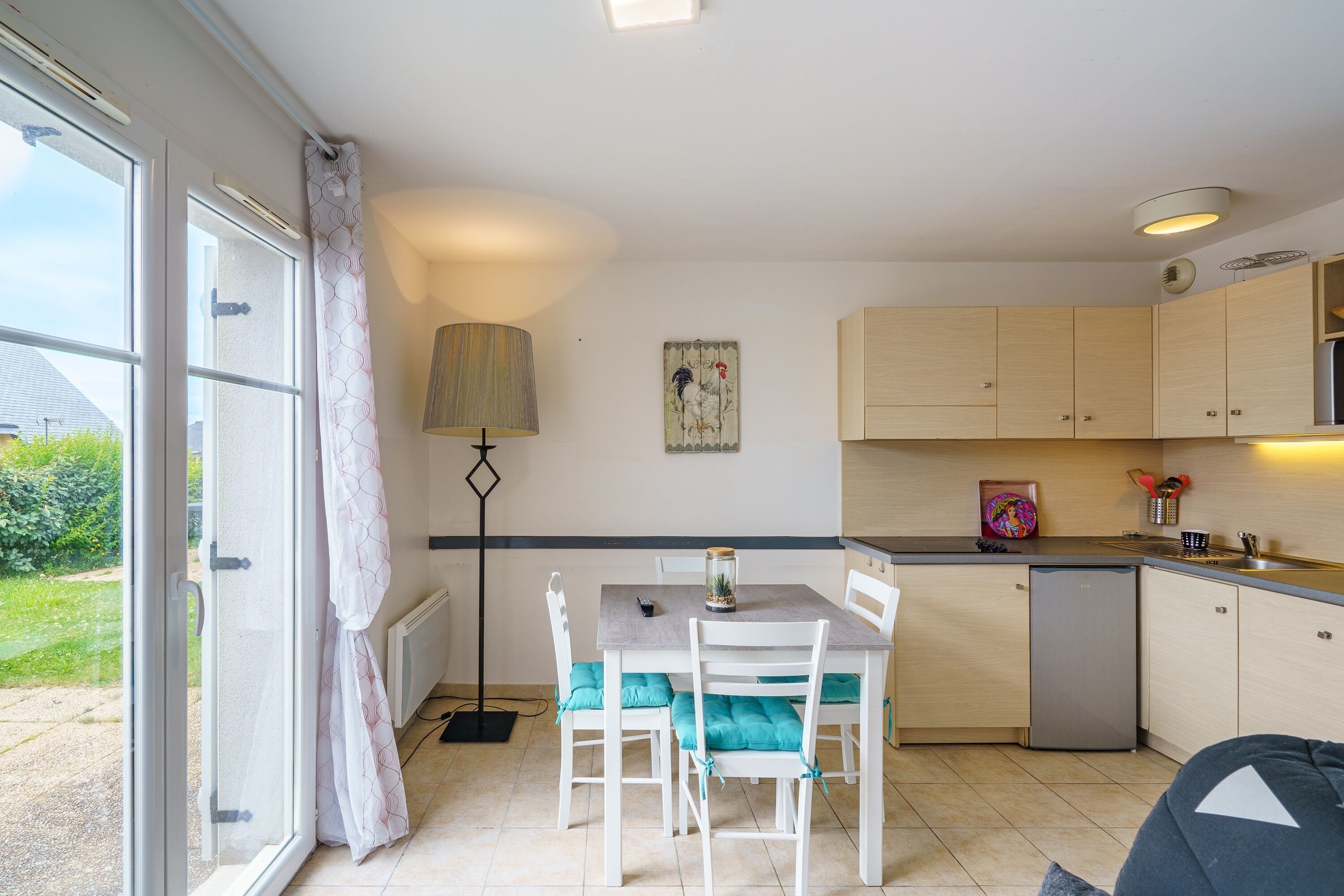 Una cocina compacta con comedor, una lámpara y vista al exterior.