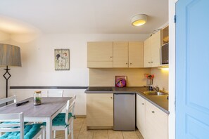 Eine kleine Küche mit Esstisch, Stühlen, Kühlschrank und Spüle.