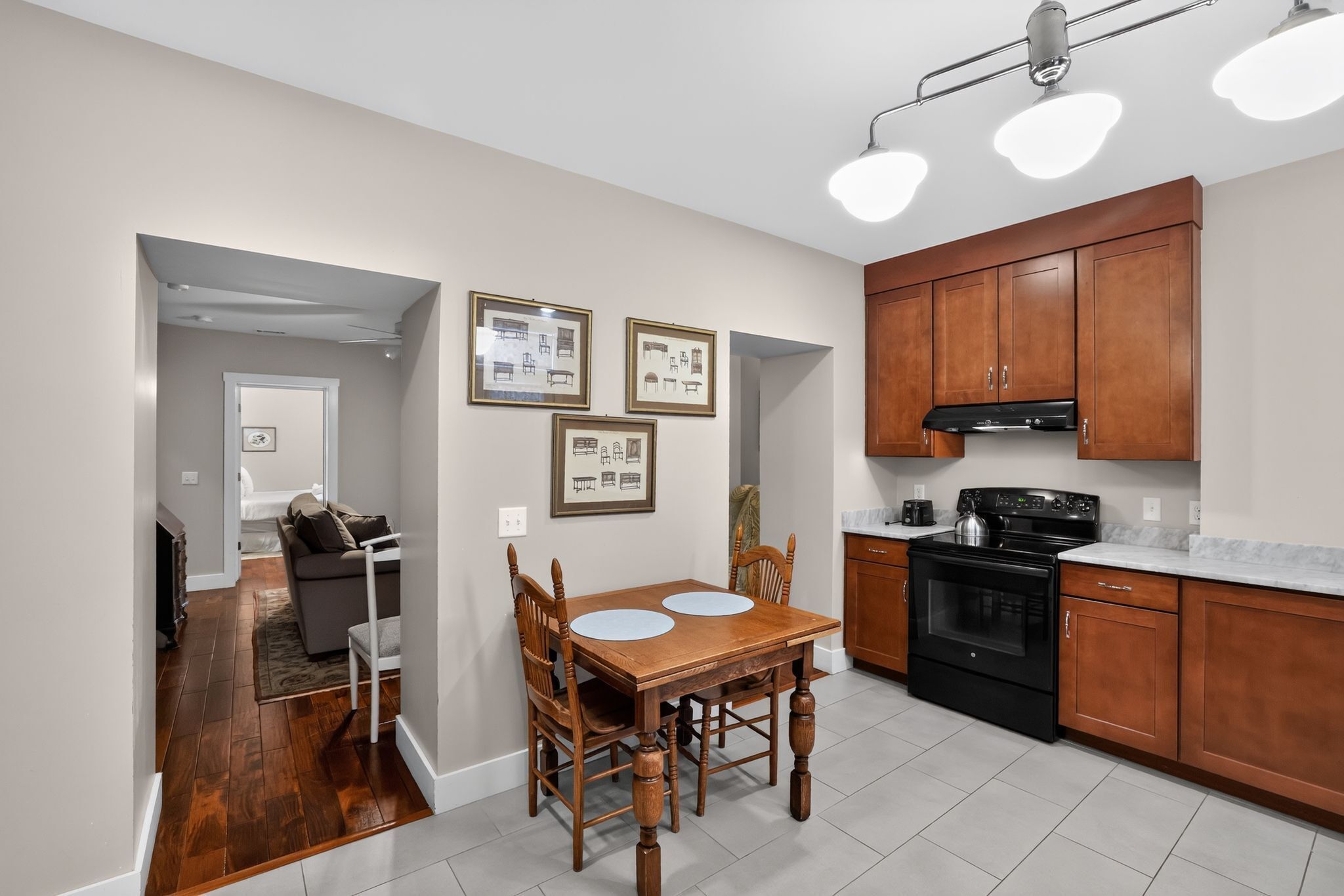 A modern kitchen with wooden cabinets, a black stove, and a dining area with a wooden table and chairs.