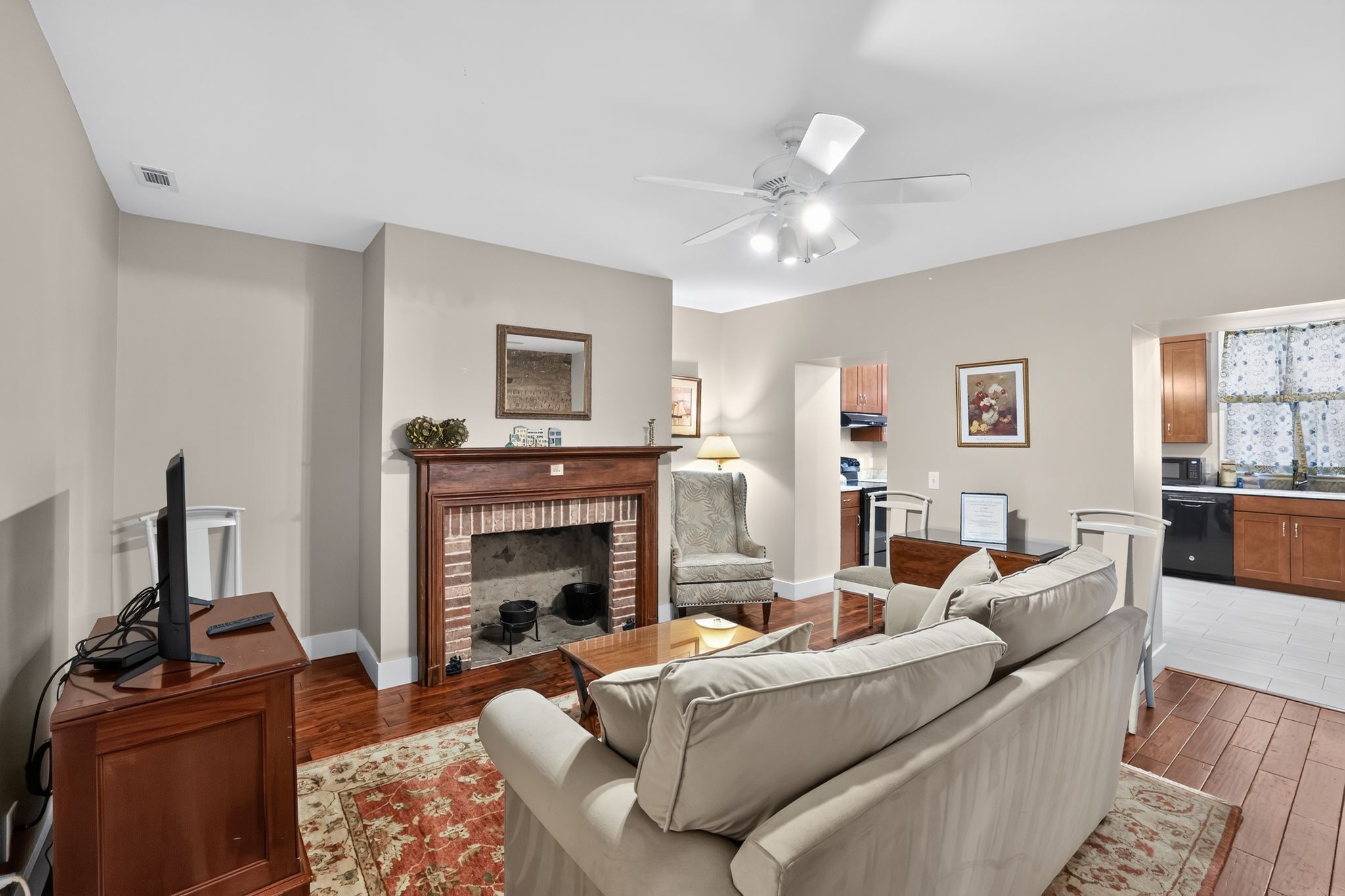 A living room with a fireplace, a sofa, a television, and a ceiling fan.