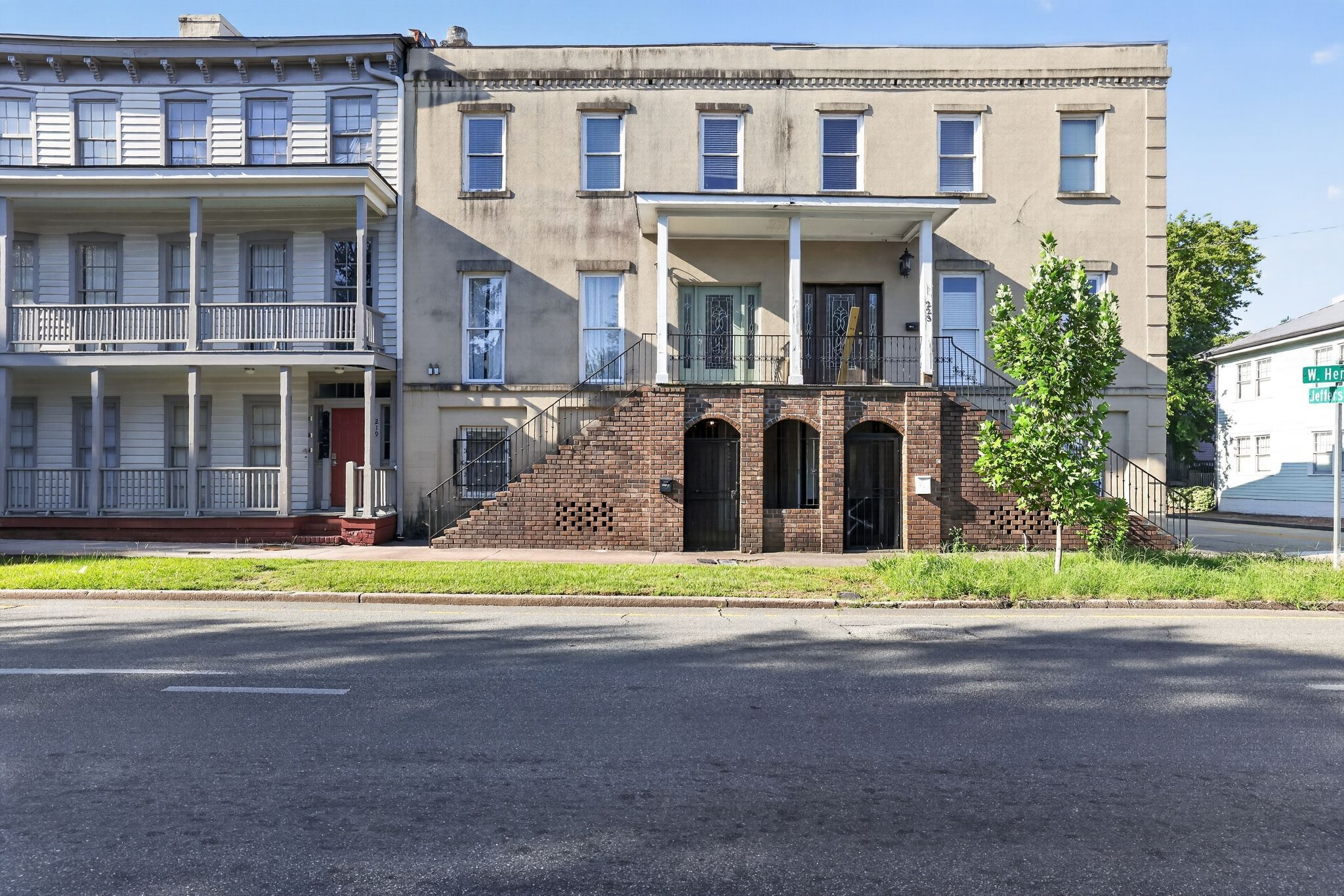 A two-story building with a brick facade, a front porch, and a street view.