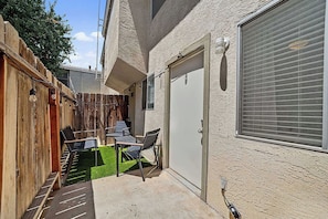 A patio with a table and chairs, a wooden fence, and a door with a window. - Quiet 2BR Retreat Fast Wi-Fi Near Dining & Shops (Bakersfield)