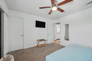A bedroom with a ceiling fan, a bed, a TV, and a small wooden chair. - Quiet 2BR Retreat Fast Wi-Fi Near Dining & Shops (Bakersfield)