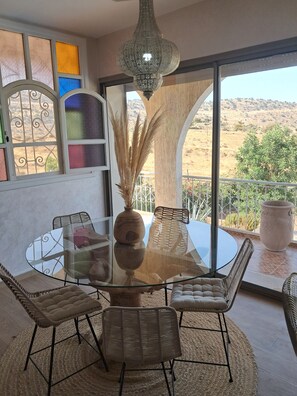 A dining area with a glass table, wicker chairs, and a decorative vase.