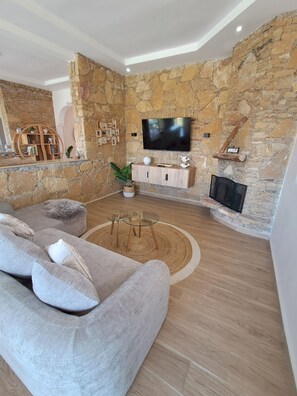 Ein Wohnzimmer mit Steinwand, Flachbildfernseher, Sofa und Kamin.