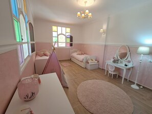 A pink-themed bedroom with a bed, a desk, a chair, a lamp, and a window.