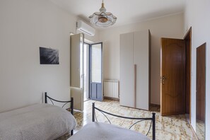 A room with two beds, a radiator, a wooden door, and a ceiling fan. - Villa Etna Pool & Seaview by Wonderful Italy (Belpasso)