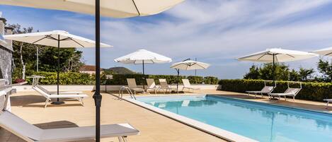 A poolside area with lounge chairs and umbrellas.