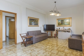 A living room with a sofa, a TV, a wooden cabinet, and two paintings on the wall. - Villa Etna Pool & Seaview by Wonderful Italy (Belpasso)