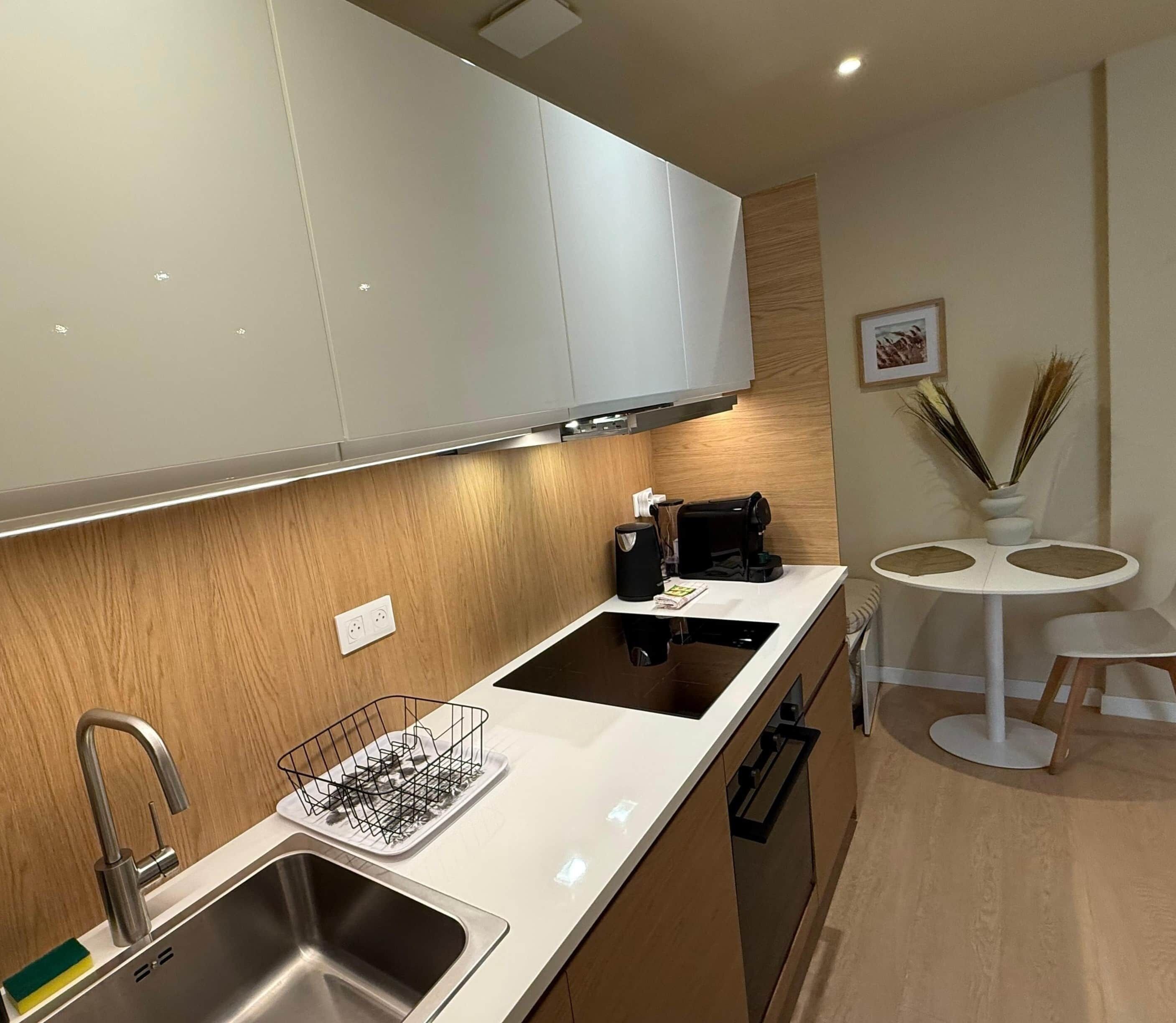 A modern kitchen with white cabinets, a stainless steel sink, and a black stove.