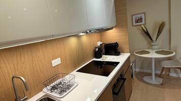 Une cuisine moderne avec des meubles blancs, un évier en acier inoxydable et une cuisinière noire.