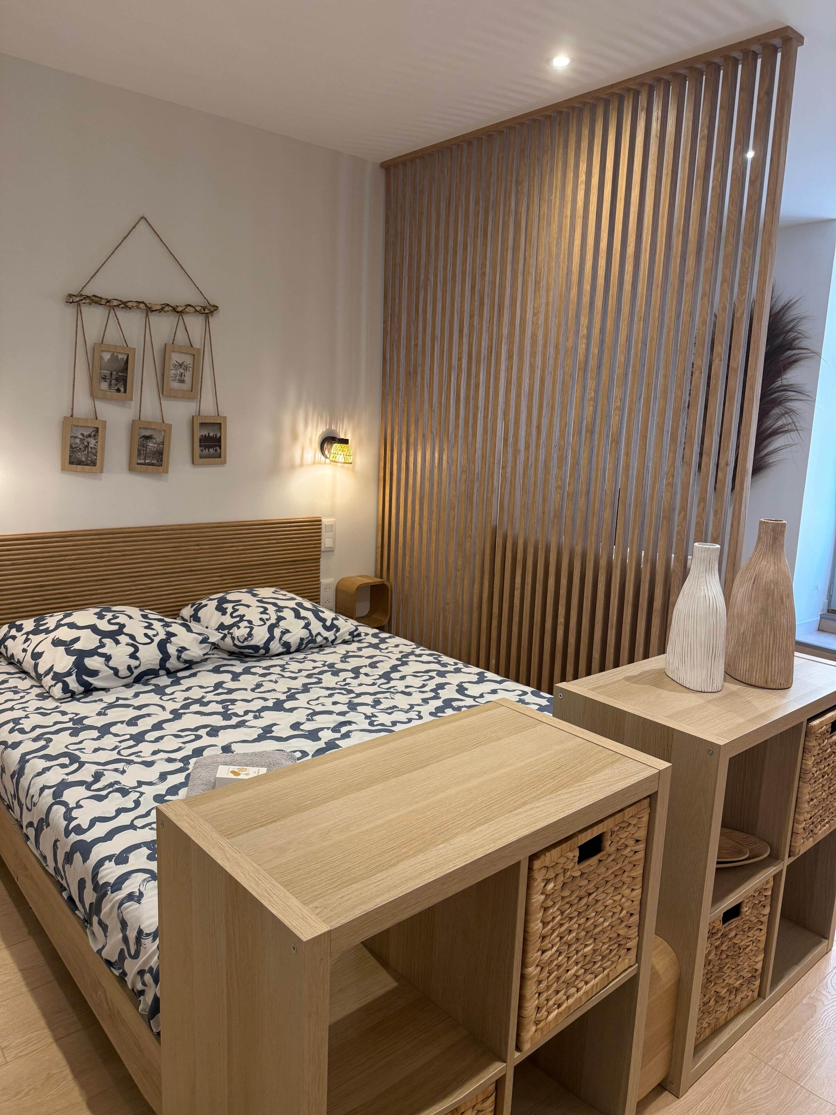 Een slaapkamer met een bed, nachtkastjes, een wandlamp en een decoratief wandpaneel.