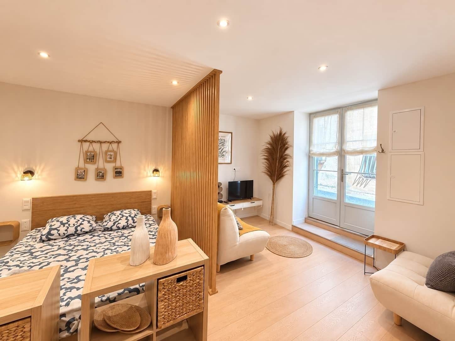 A modern bedroom with a bed, bedside tables, a desk, and a window.