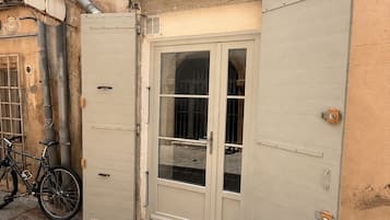 Un bâtiment doté d’une grande porte en métal, avec un vélo garé à l’extérieur et des tuyaux apparents sur le mur.