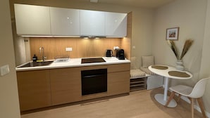 A compact kitchen with a sink, stove, and a small dining area with a table and chairs. - La Bohème - Historic City Centre Studio – Aix Cours Mirabeau (Aix-en-Provence)
