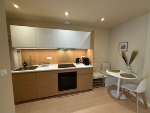 A compact kitchen with a sink, stove, and a small dining area with a table and chairs. - La Bohème - Historic City Centre Studio – Aix Cours Mirabeau (Aix-en-Provence)