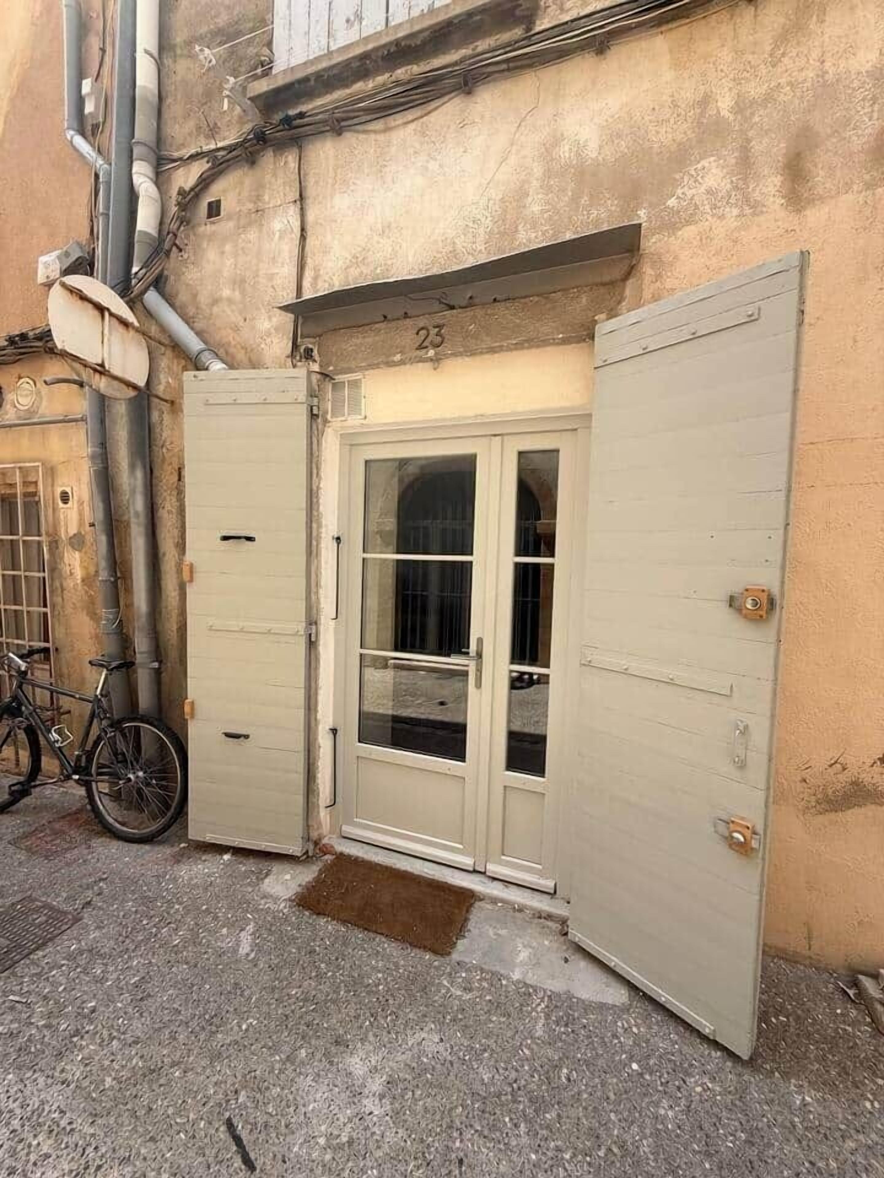 A building entrance with a glass door, a bicycle parked outside, and a number '23' on the wall.