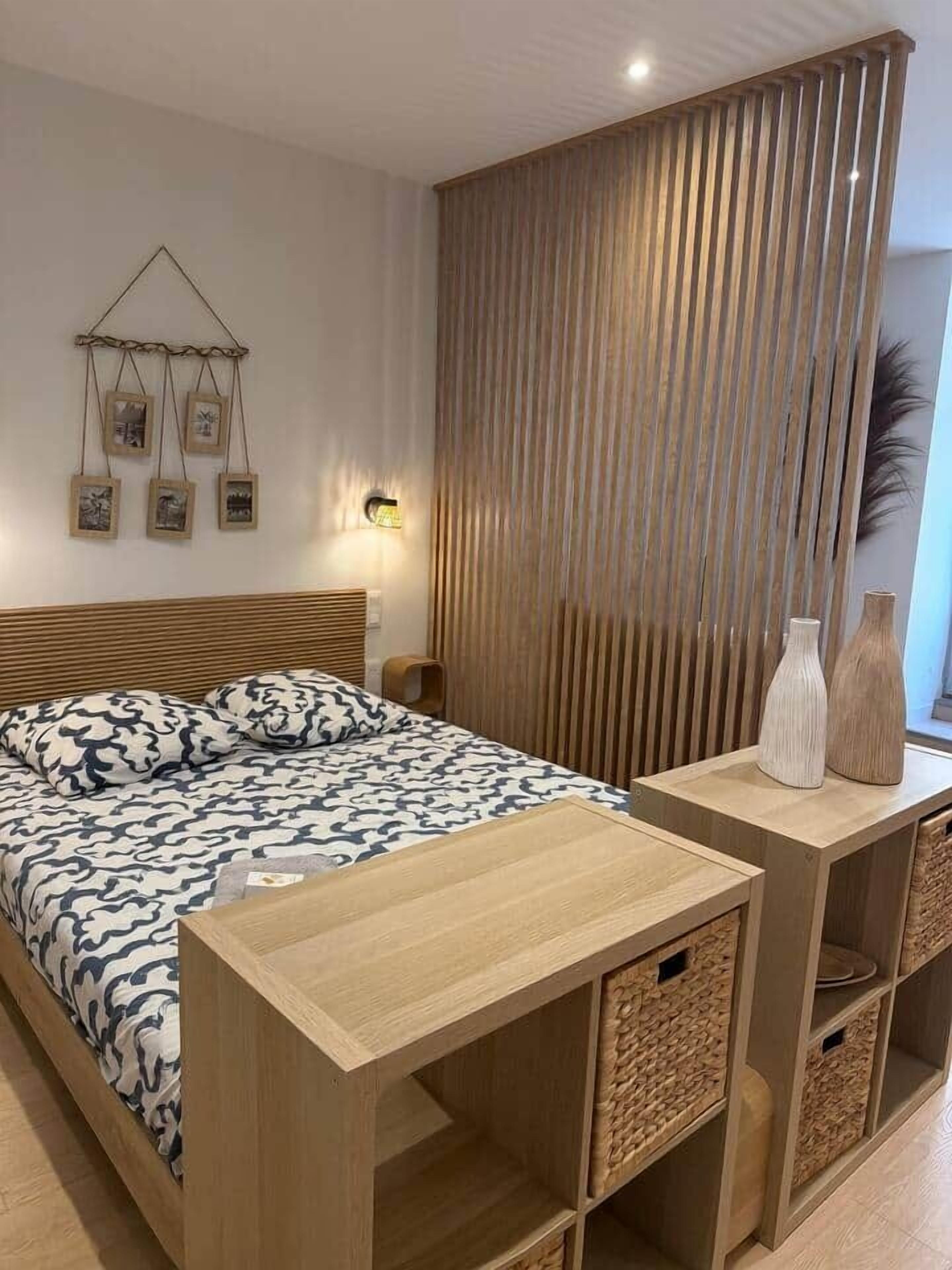 Un dormitori modern amb un llit de fusta, taules de nit i un panell decoratiu a la paret.