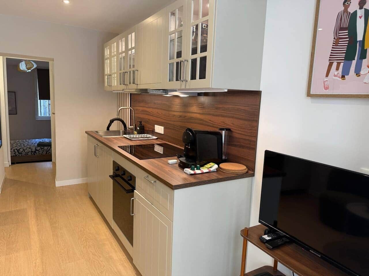 Een moderne keuken met een ingebouwde oven, een koffieapparaat en een flatscreen televisie.