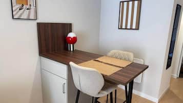 A compact dining area with a wooden table, a single chair, and a small cabinet.