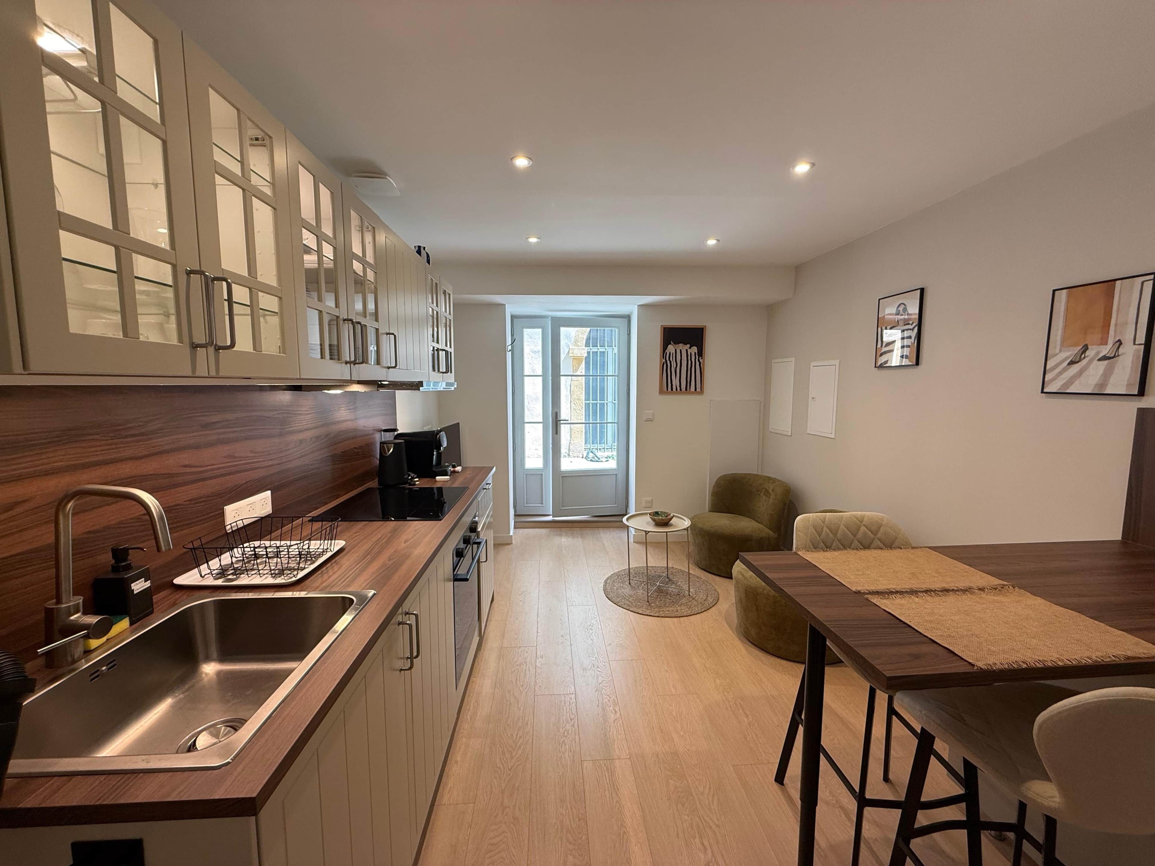 A modern kitchen with a built-in oven, a stainless steel sink, and wooden cabinets.