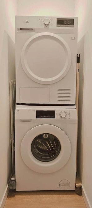 Eine kompakte, an der Wand befestigte Wascher- und Trockner-Kombination in einem schmalen Flur.