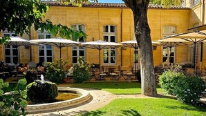 Um pátio com área de estar externa, uma fonte e um edifício com várias janelas.