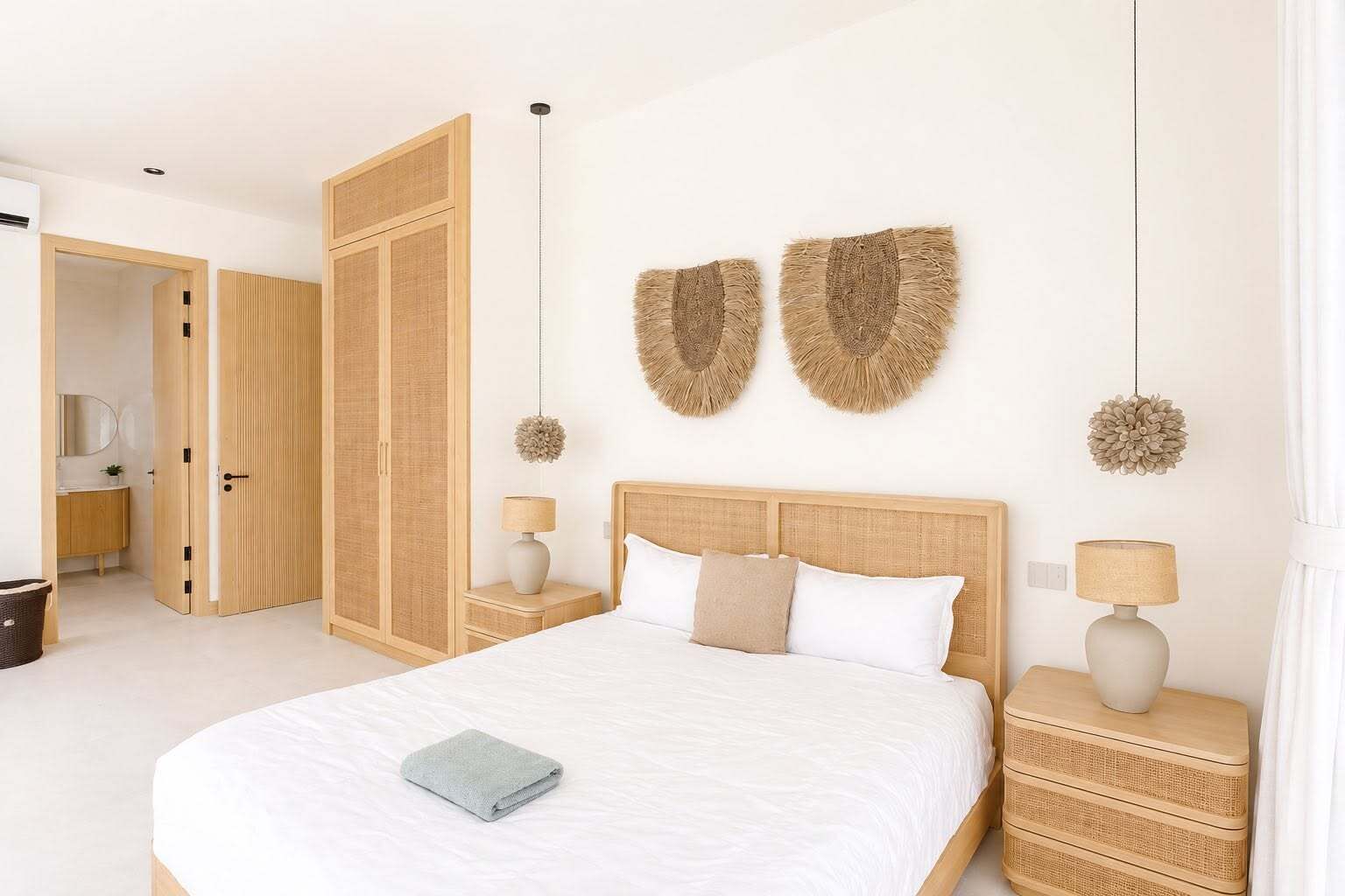 Une chambre avec un grand lit, une armoire en bois, deux lampes fixées au mur et un luminaire suspendu.
