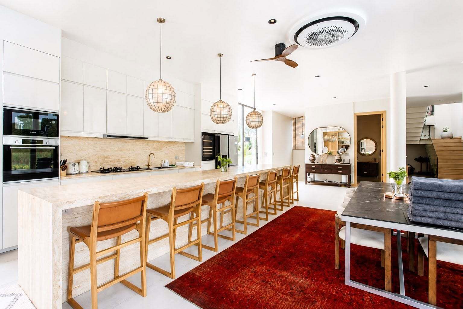 A modern kitchen with a central island, bar stools, and pendant lighting.