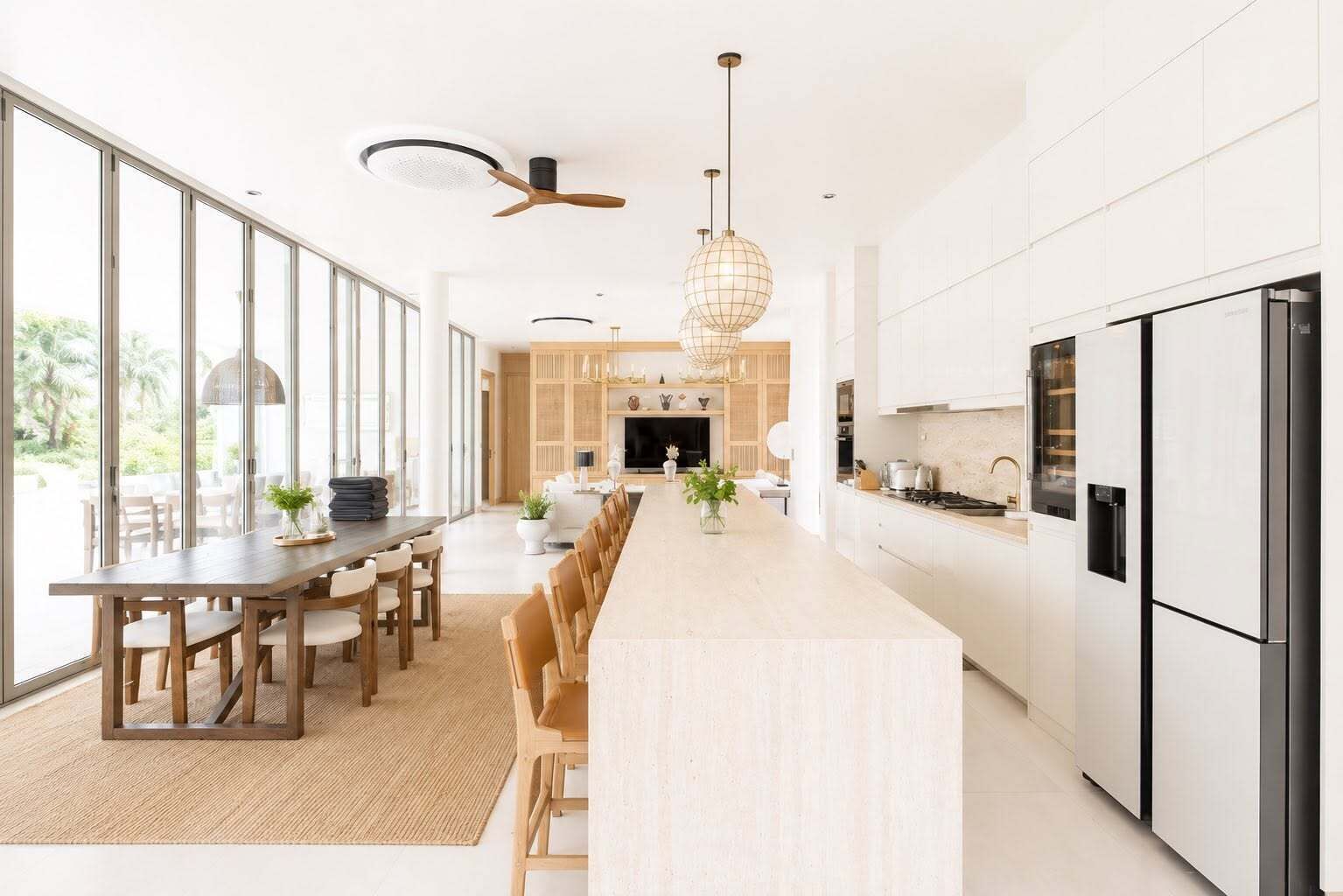 Une cuisine moderne dotée d’un îlot central, de grandes fenêtres et d’un coin repas.