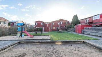 A residential area with a playground, a grassy yard, and red buildings.