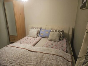 Un dormitorio con una cama, un armario de madera y una lámpara de pared.