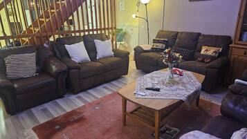 A living room with two sofas, a coffee table, and a staircase.