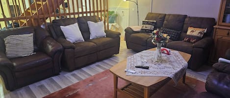 A living room with two sofas, a coffee table, and a staircase.