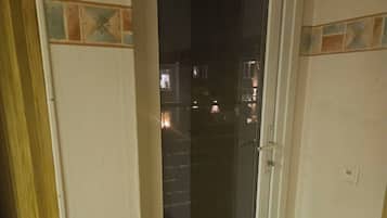 A room with a sliding glass door leading to an outdoor area, a small rug on the floor, and a visible electrical outlet on the wall.
