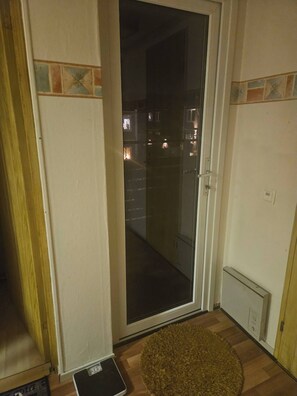 Una habitación con puerta corrediza de vidrio que da a un espacio exterior, una alfombra pequeña en el suelo y un enchufe visible en la pared.