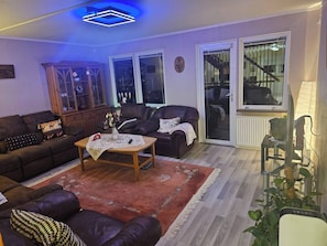 Una sala de estar con sofá, sillón, mesa de centro y aparador.