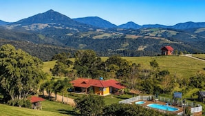 A property with a swimming pool, a red-roofed building, and a view of distant mountains.