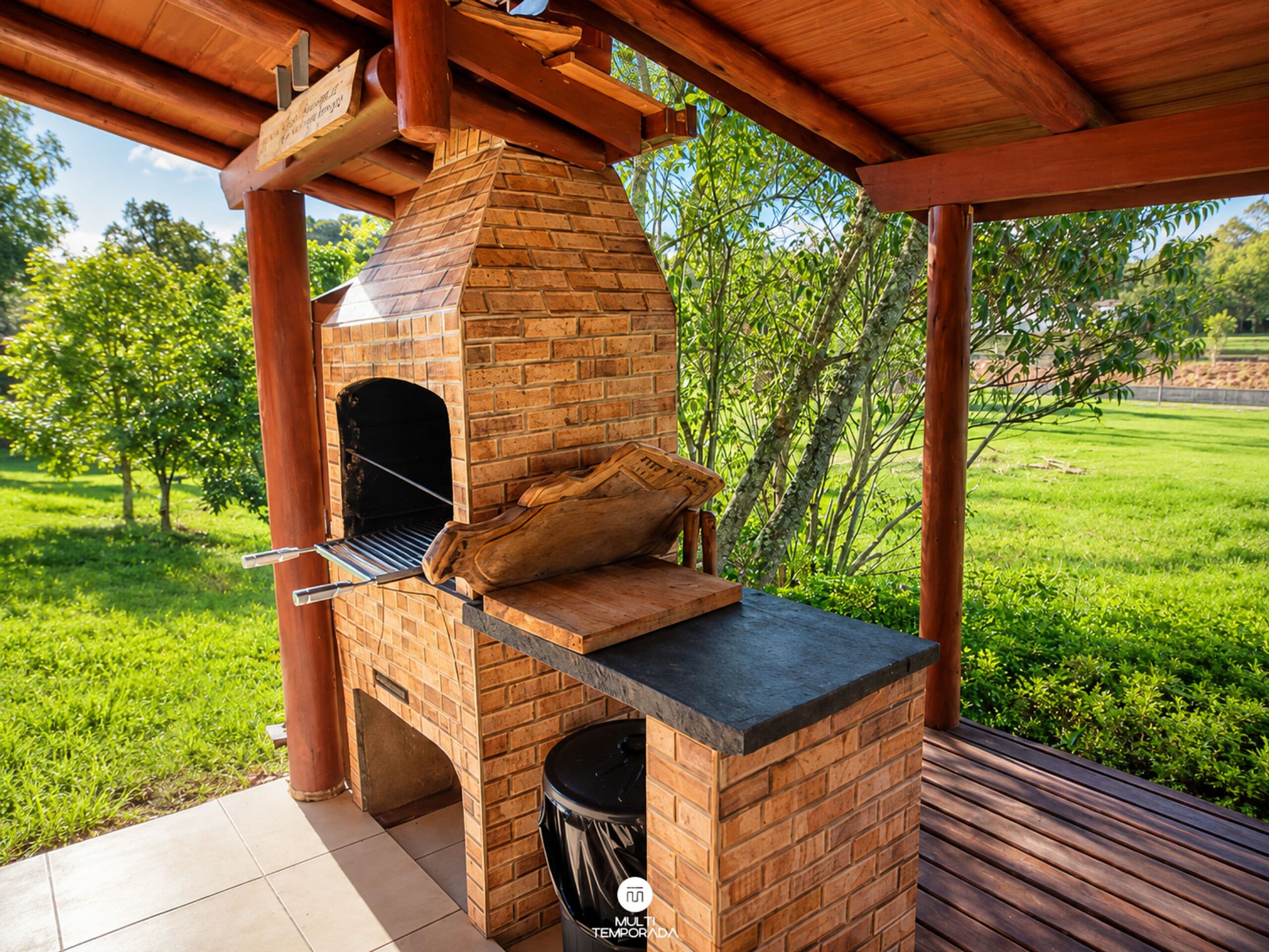 An outdoor brick oven with a chimney, located on a covered patio with a tiled floor.